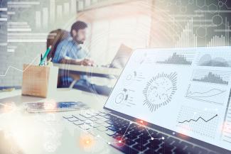Double exposure of  businessman working in modern office with data graphs popping out of laptop in foreground