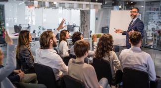 Mature businessman talking to large group of people on a business presentation in a board room