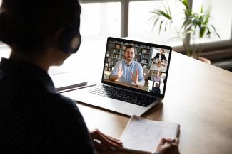 Laptop screen view over woman shoulder during group videocall
