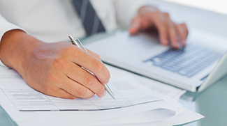 Business man reviewing paper documents and laptop