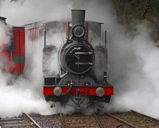 West Coast Wilderness Railway black narrow gauge steam engine puffs clouds of steam