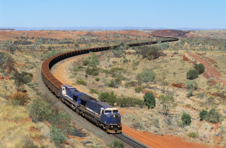 Trains carries a load of iron ore through a rugged desert landscape in outback Western Australia